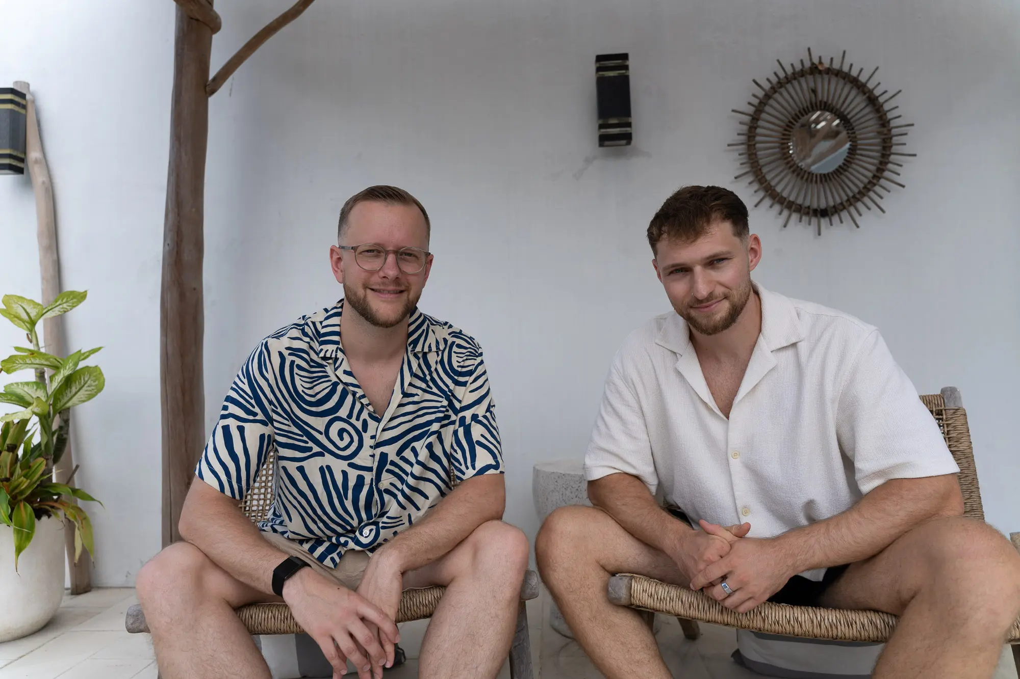 Tim und Felix lachen nebeneinander auf Rattanstühlen