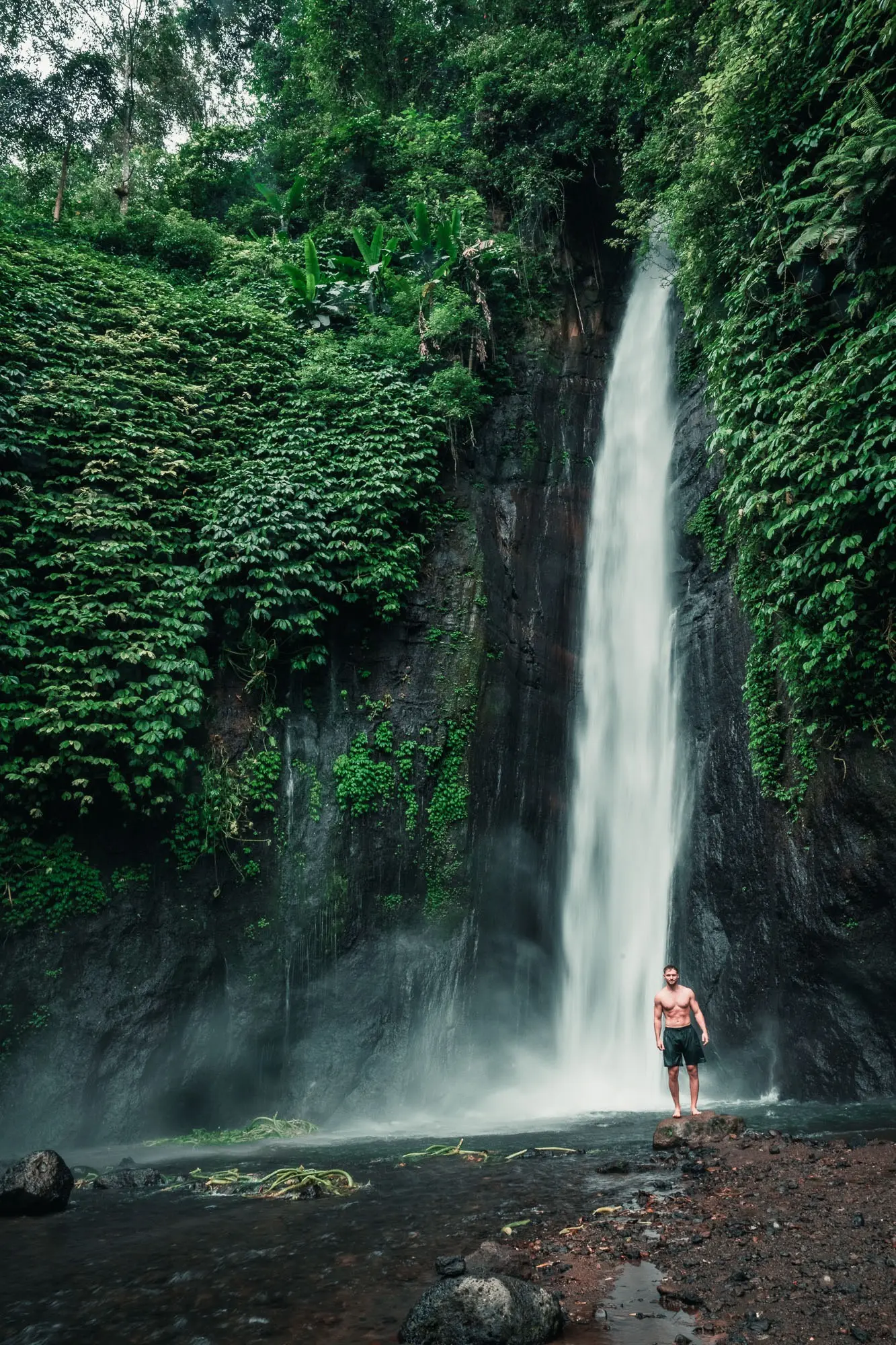 Felix steht vor einem Wasserfall im Dschungel auf Bali