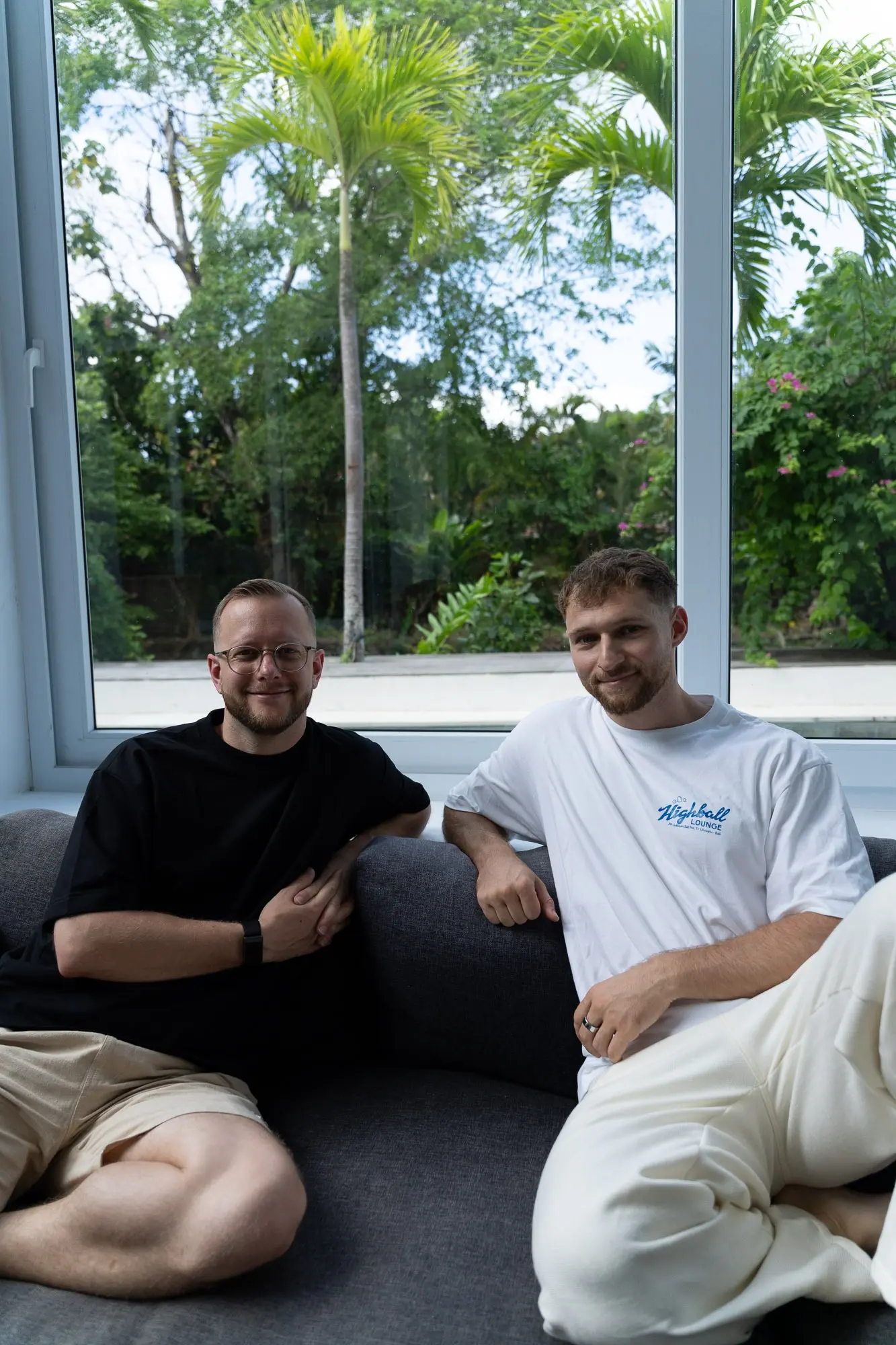Tim und Felix sitzen lachend auf dem Sofa in der Villa auf Bali