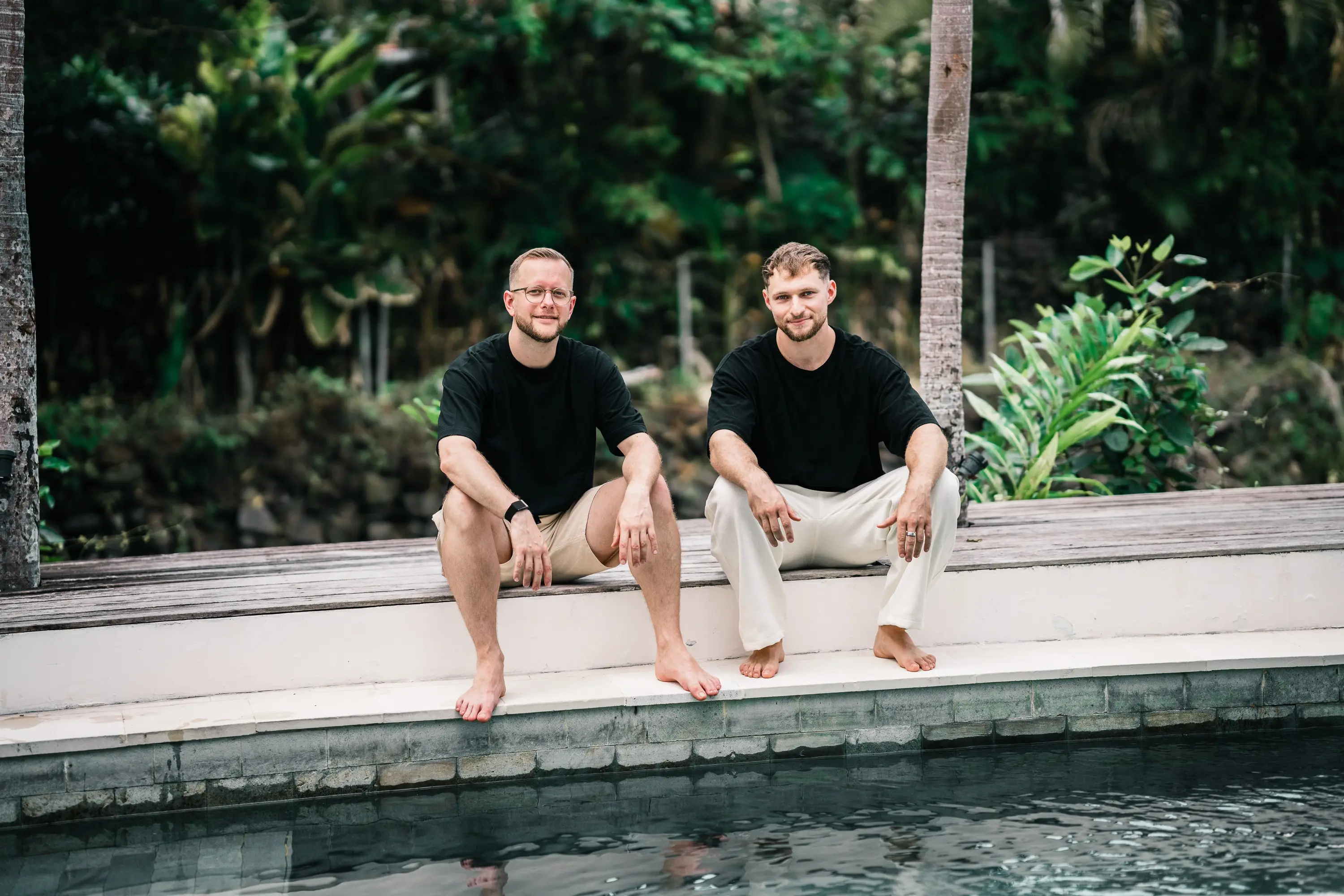 Felix und Tim sitzen barfuß am Poolrand
