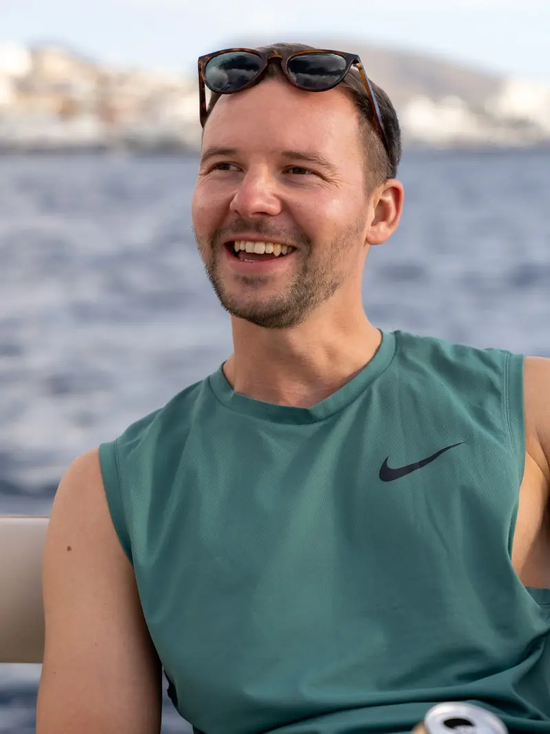 Micha lacht auf einem Boot vor dem Meer