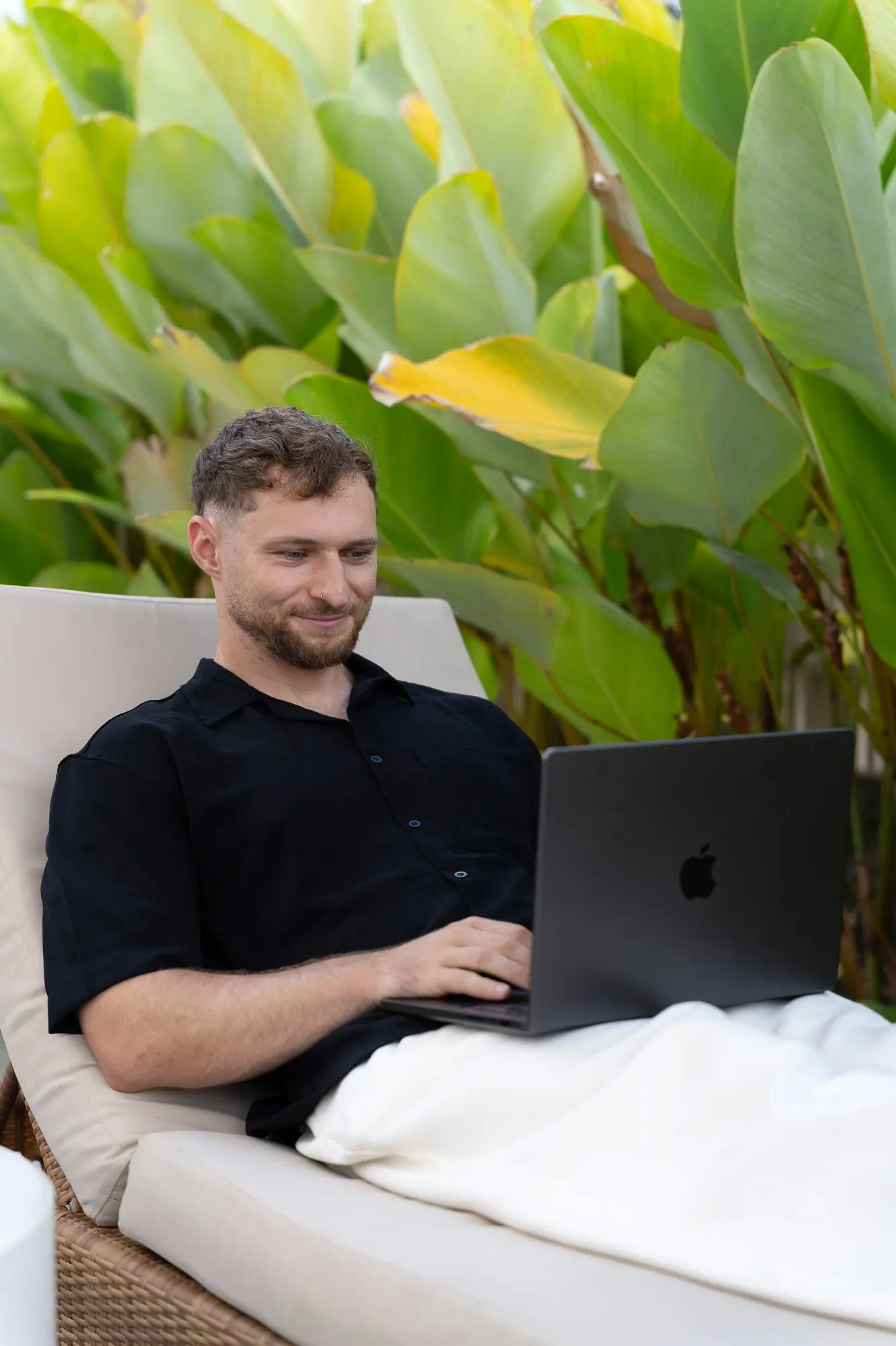 Felix arbeitet am Laptop auf einer Liege im Grünen