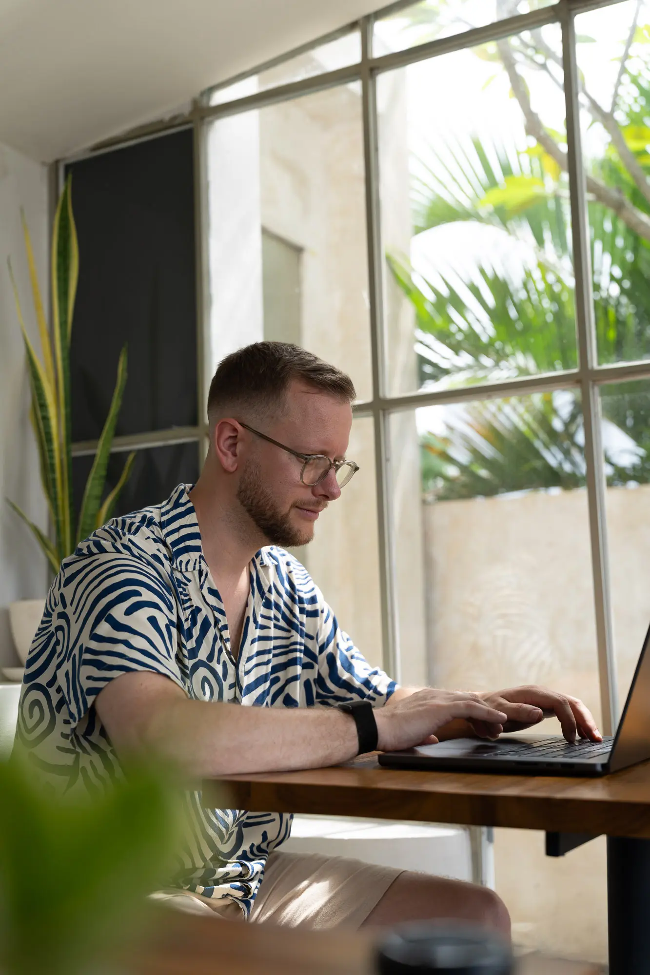 Tim arbeitet konzentriert am Laptop an einem hellen Fenster