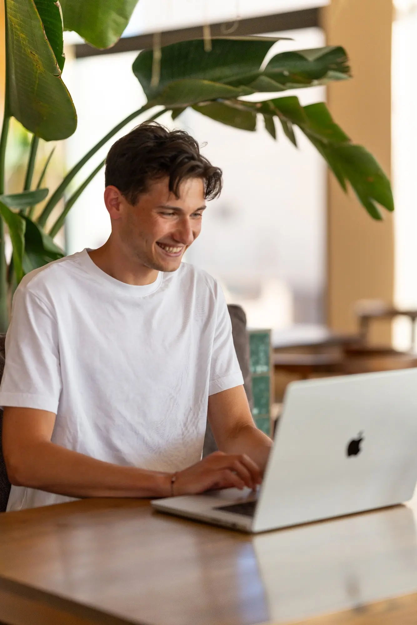 Franz lacht beim Arbeiten am Laptop