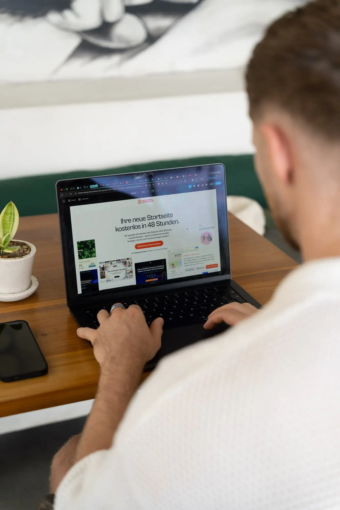 Blick über die Schulter auf einen Laptop mit Pflanze