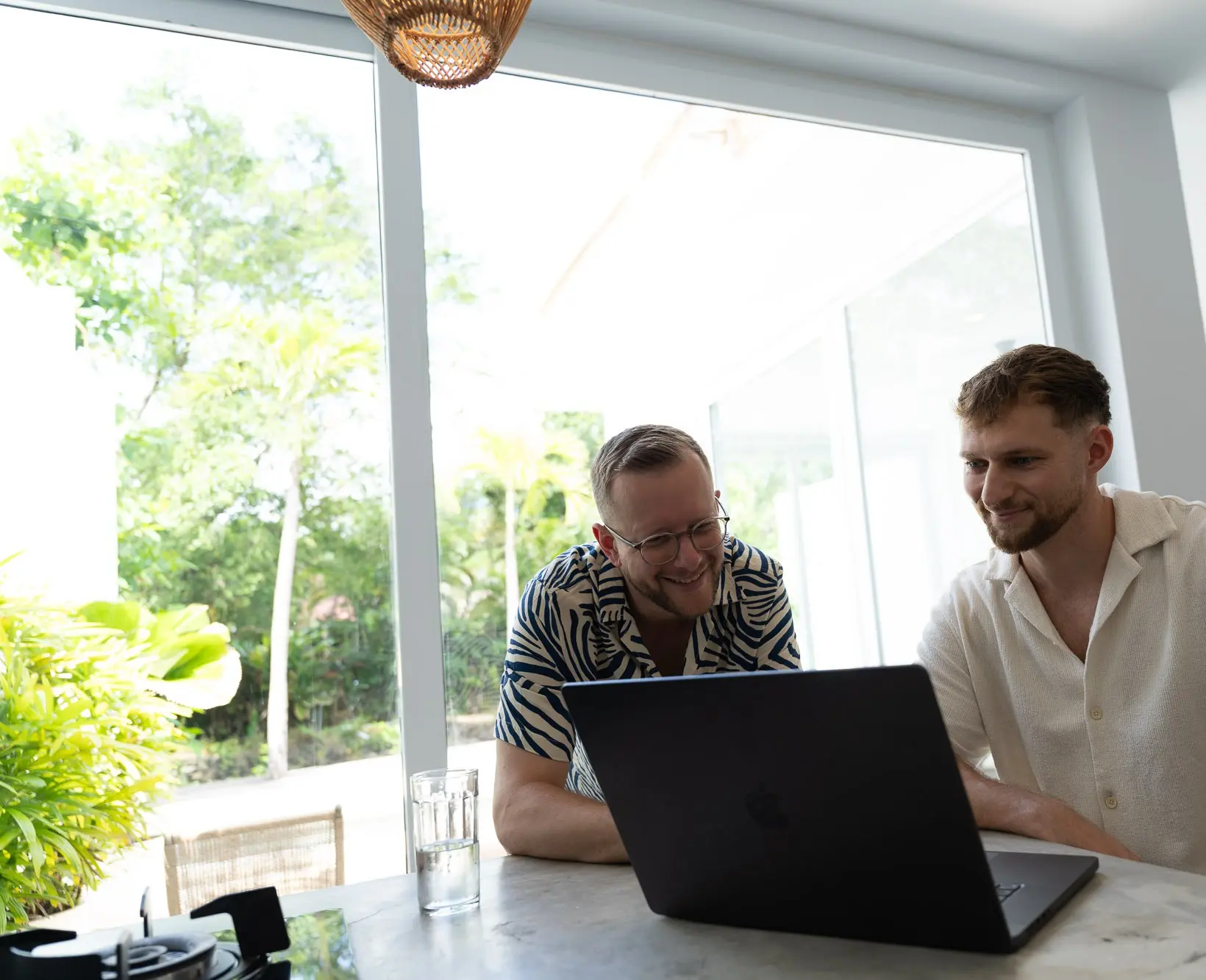 Felix und Tim arbeiten lachend gemeinsam am Laptop