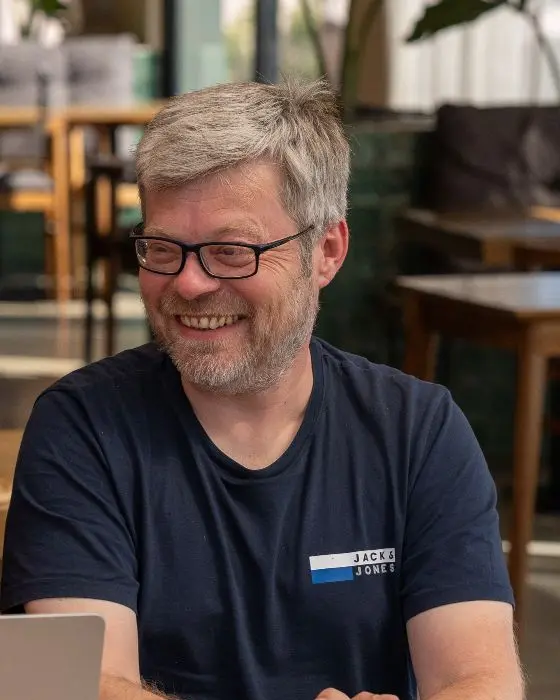 Manuel lacht am Laptop im Café